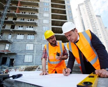Construction site with project manager and builder discussing the project and deciding how to proceed.